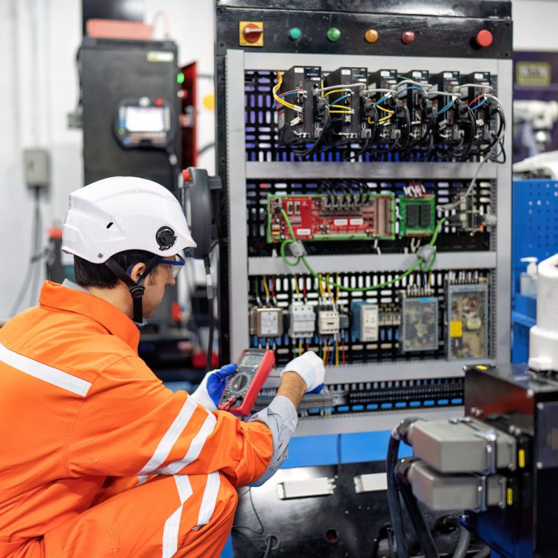 Engineer hold multimeter testing cable wiring robotic control panel at robot maintenance shop